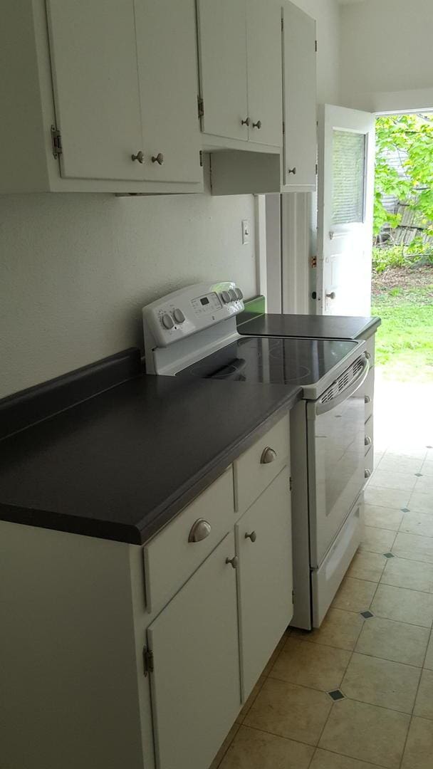 kitchen featuring white cabinetry, white electric range oven, and light tile patterned floors