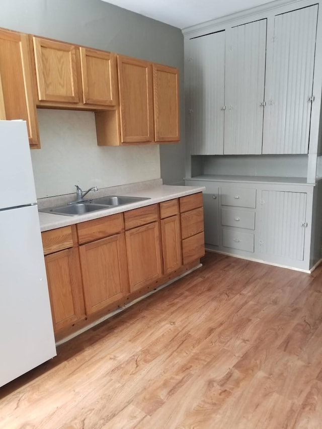 kitchen featuring white refrigerator, sink, and light hardwood / wood-style flooring