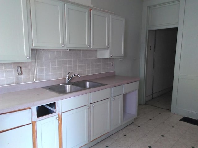 kitchen with tasteful backsplash, sink, and white cabinets