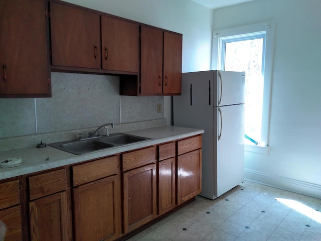 kitchen featuring decorative backsplash, sink, and white fridge