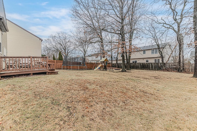 view of yard featuring a playground, a wooden deck, and a trampoline