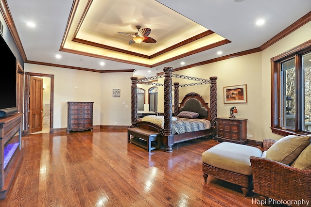 bedroom with hardwood / wood-style flooring, crown molding, and a raised ceiling