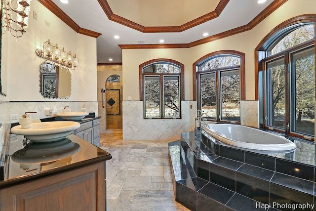 bathroom with tiled tub, vanity, tile walls, and crown molding