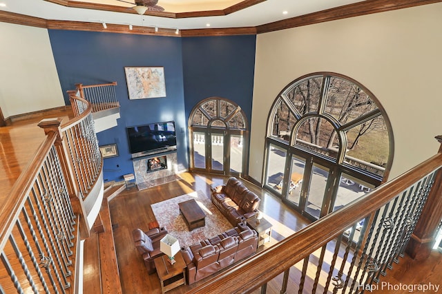 living room featuring crown molding, dark wood-type flooring, a healthy amount of sunlight, and a high ceiling