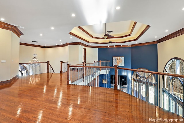 hall featuring an inviting chandelier, hardwood / wood-style flooring, ornamental molding, and a tray ceiling