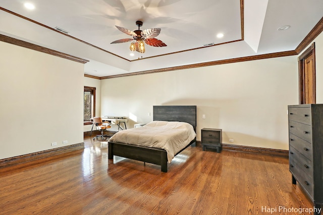 bedroom featuring a raised ceiling, crown molding, hardwood / wood-style floors, and ceiling fan