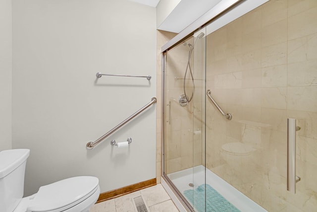 bathroom featuring tile patterned floors, toilet, and a shower with door