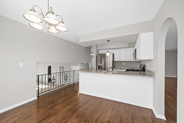 kitchen with white cabinetry, appliances with stainless steel finishes, kitchen peninsula, and light stone countertops