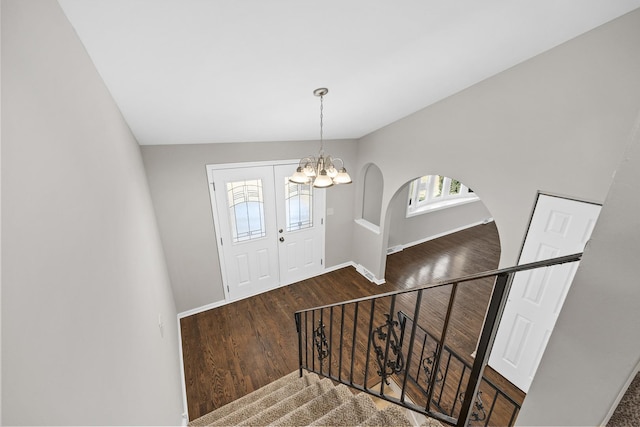 entryway featuring dark wood-type flooring and a chandelier