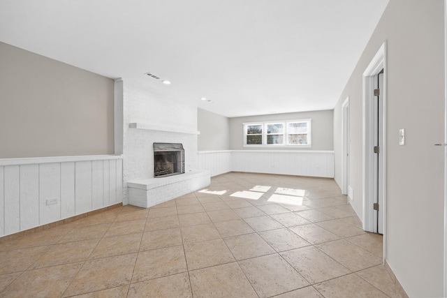 unfurnished living room featuring a fireplace and light tile patterned flooring