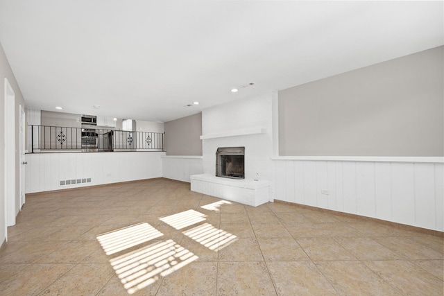 unfurnished living room with a brick fireplace and light tile patterned floors