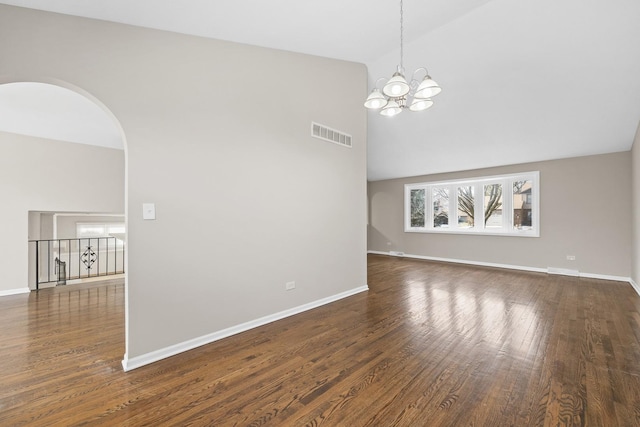 spare room with dark hardwood / wood-style floors, high vaulted ceiling, and a notable chandelier