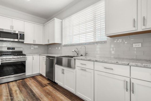 kitchen with white cabinetry, appliances with stainless steel finishes, backsplash, and crown molding