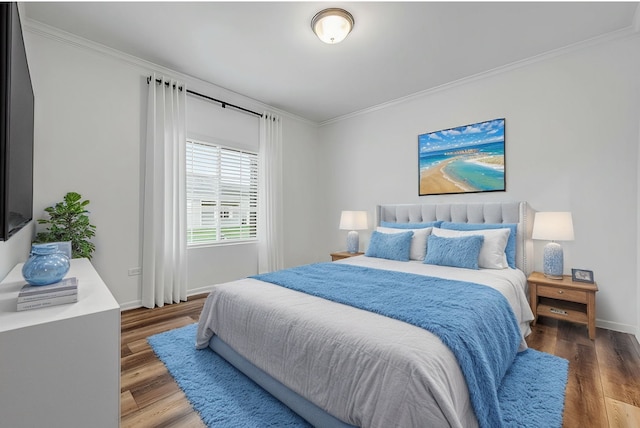 bedroom featuring crown molding, baseboards, and wood finished floors