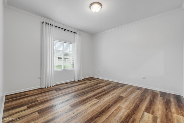 spare room with baseboards, wood finished floors, and crown molding