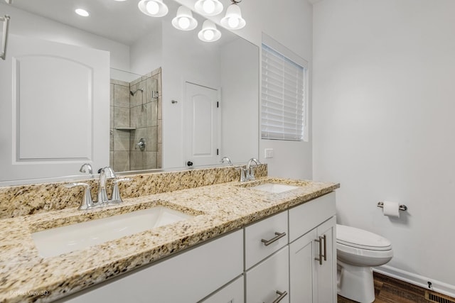 full bath with toilet, a shower stall, double vanity, and a sink