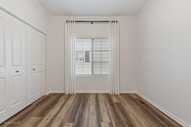 interior space with crown molding, a closet, baseboards, and wood finished floors