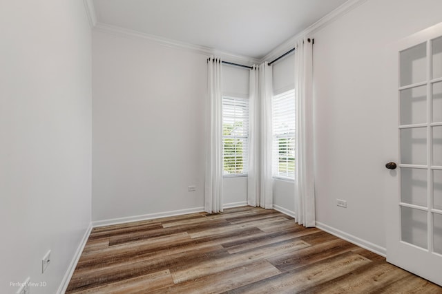 spare room with crown molding, baseboards, and wood finished floors