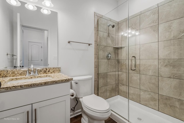 bathroom featuring vanity, a shower stall, and toilet