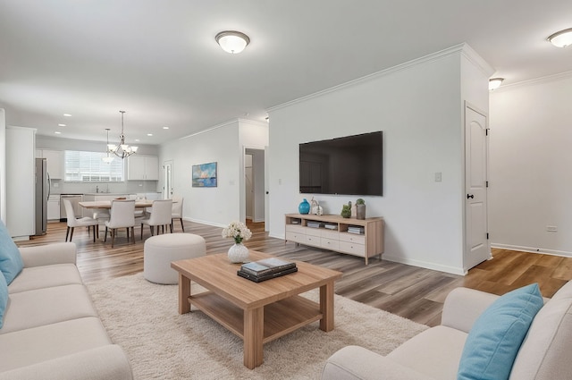 living area featuring ornamental molding, baseboards, a notable chandelier, and light wood finished floors