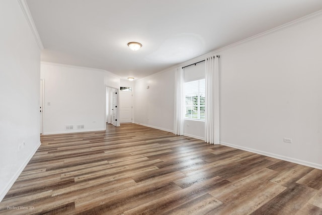 unfurnished room with ornamental molding, wood finished floors, and baseboards