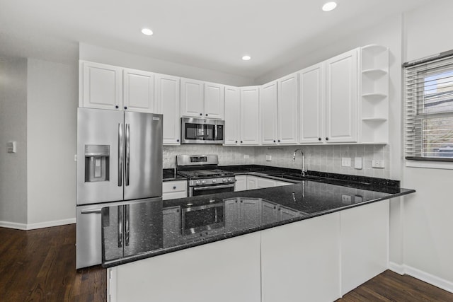 kitchen featuring sink, dark stone countertops, appliances with stainless steel finishes, kitchen peninsula, and white cabinets