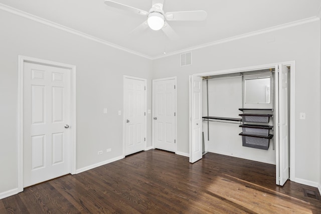 unfurnished bedroom with crown molding, ceiling fan, dark hardwood / wood-style floors, and two closets