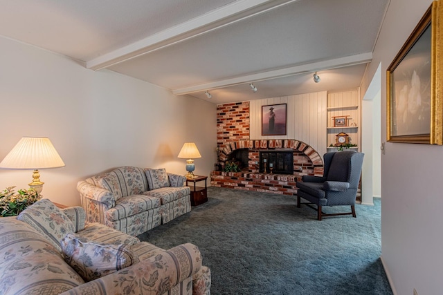 living room with a brick fireplace, carpet floors, rail lighting, and beamed ceiling