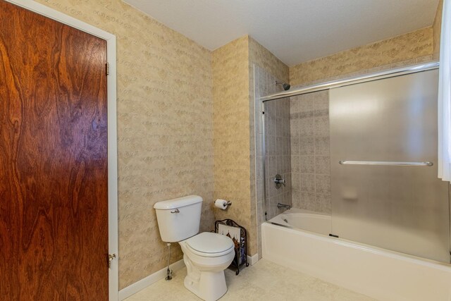 bathroom featuring bath / shower combo with glass door and toilet