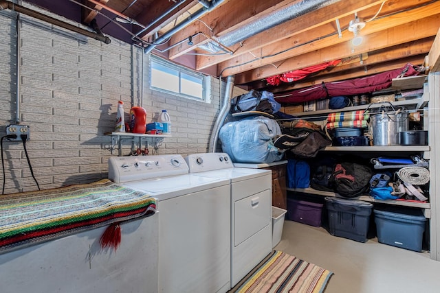 laundry room featuring washing machine and clothes dryer and brick wall