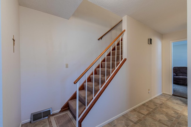 stairway featuring a textured ceiling