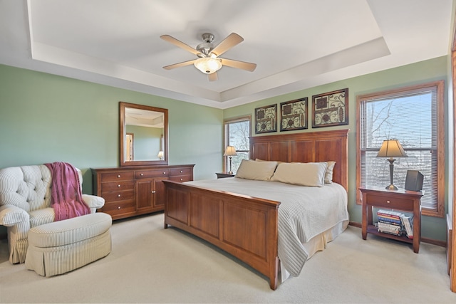 carpeted bedroom featuring a tray ceiling and ceiling fan