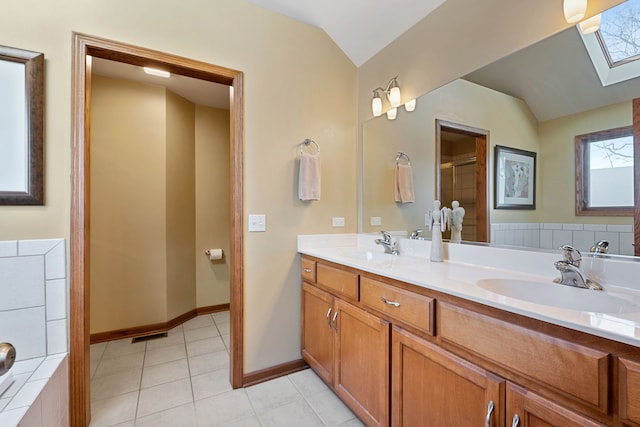 bathroom with vanity, vaulted ceiling with skylight, and tile patterned flooring