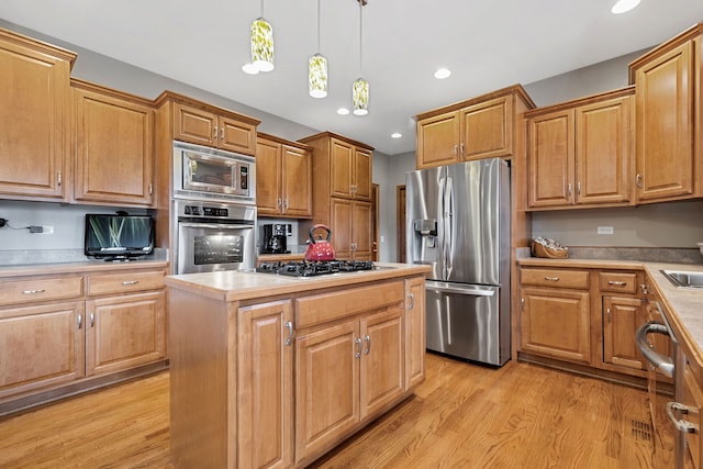 kitchen with sink, a center island, light hardwood / wood-style flooring, appliances with stainless steel finishes, and pendant lighting