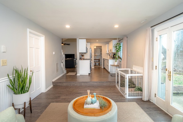 living room featuring dark wood-type flooring, ceiling fan, and a wealth of natural light