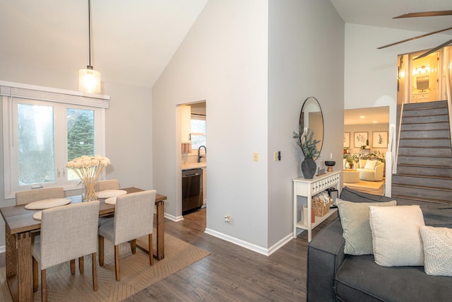 dining space with dark wood-type flooring, sink, and high vaulted ceiling