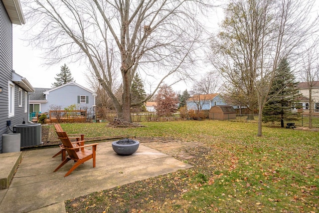 view of yard with an outdoor fire pit, a shed, a patio, and central air condition unit