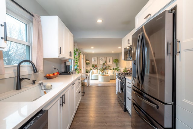 kitchen featuring stainless steel appliances, white cabinetry, sink, and dark wood-type flooring