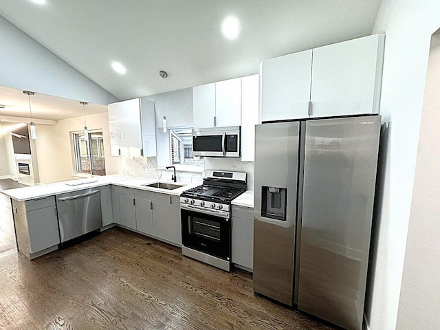 kitchen featuring appliances with stainless steel finishes, white cabinetry, sink, dark hardwood / wood-style flooring, and kitchen peninsula