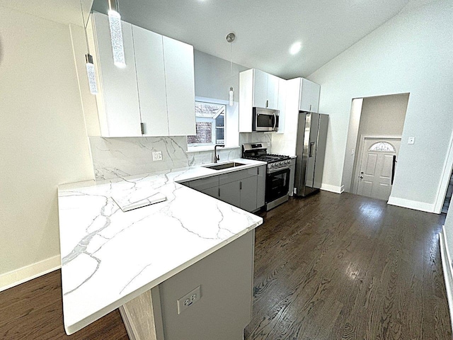 kitchen featuring sink, white cabinetry, light stone counters, appliances with stainless steel finishes, and kitchen peninsula