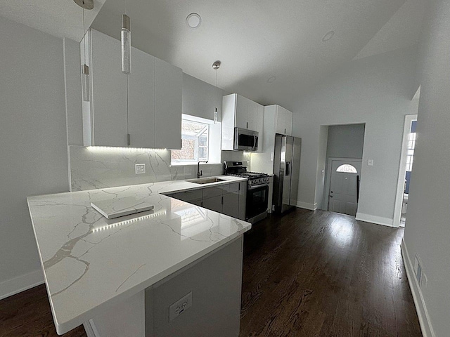 kitchen with sink, decorative light fixtures, kitchen peninsula, stainless steel appliances, and white cabinets