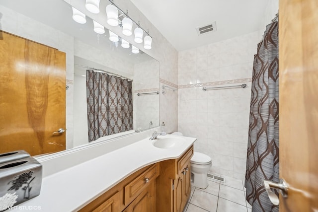 bathroom with vanity, toilet, tile patterned flooring, and tile walls