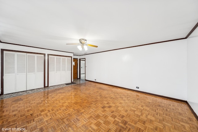 unfurnished bedroom featuring ceiling fan, crown molding, light parquet floors, and two closets