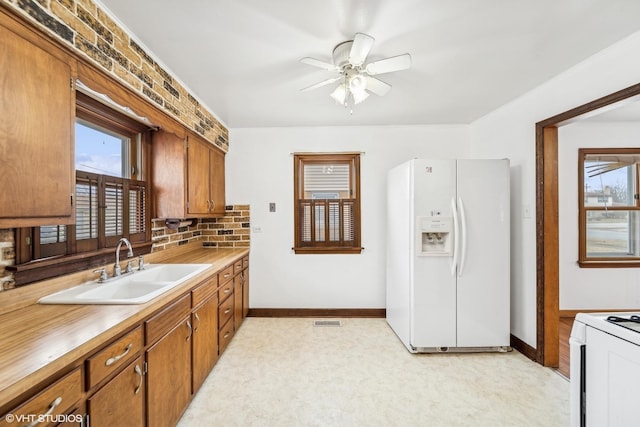 kitchen with ceiling fan, sink, white appliances, and decorative backsplash