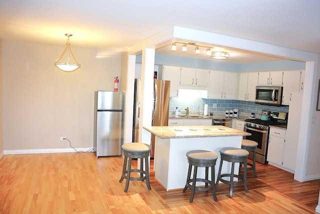 kitchen featuring sink, tasteful backsplash, hanging light fixtures, appliances with stainless steel finishes, and white cabinets