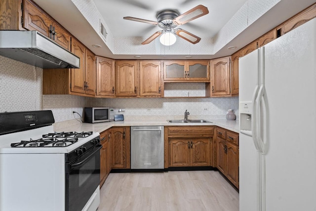 kitchen featuring stainless steel appliances, sink, decorative backsplash, and light wood-type flooring