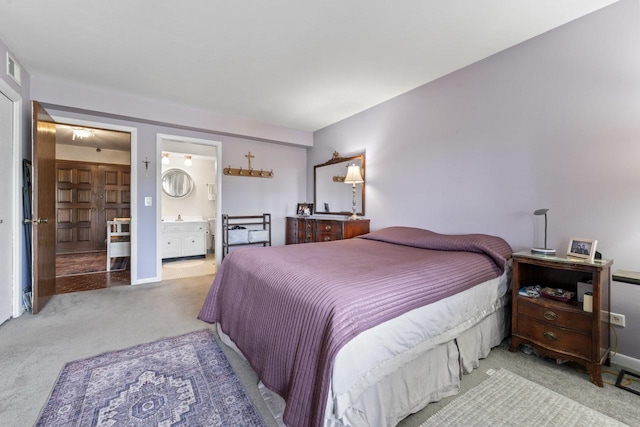 bedroom featuring ensuite bathroom and light carpet