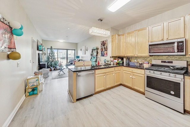 kitchen featuring pendant lighting, sink, stainless steel appliances, light brown cabinetry, and kitchen peninsula