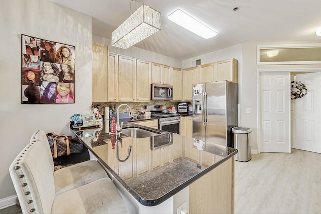 kitchen with stainless steel appliances, dark stone countertops, a kitchen breakfast bar, and kitchen peninsula