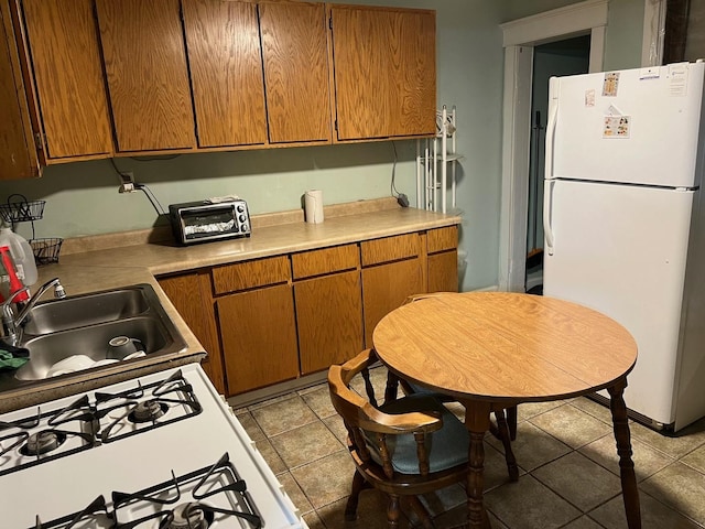 kitchen with white appliances, sink, and light tile patterned floors